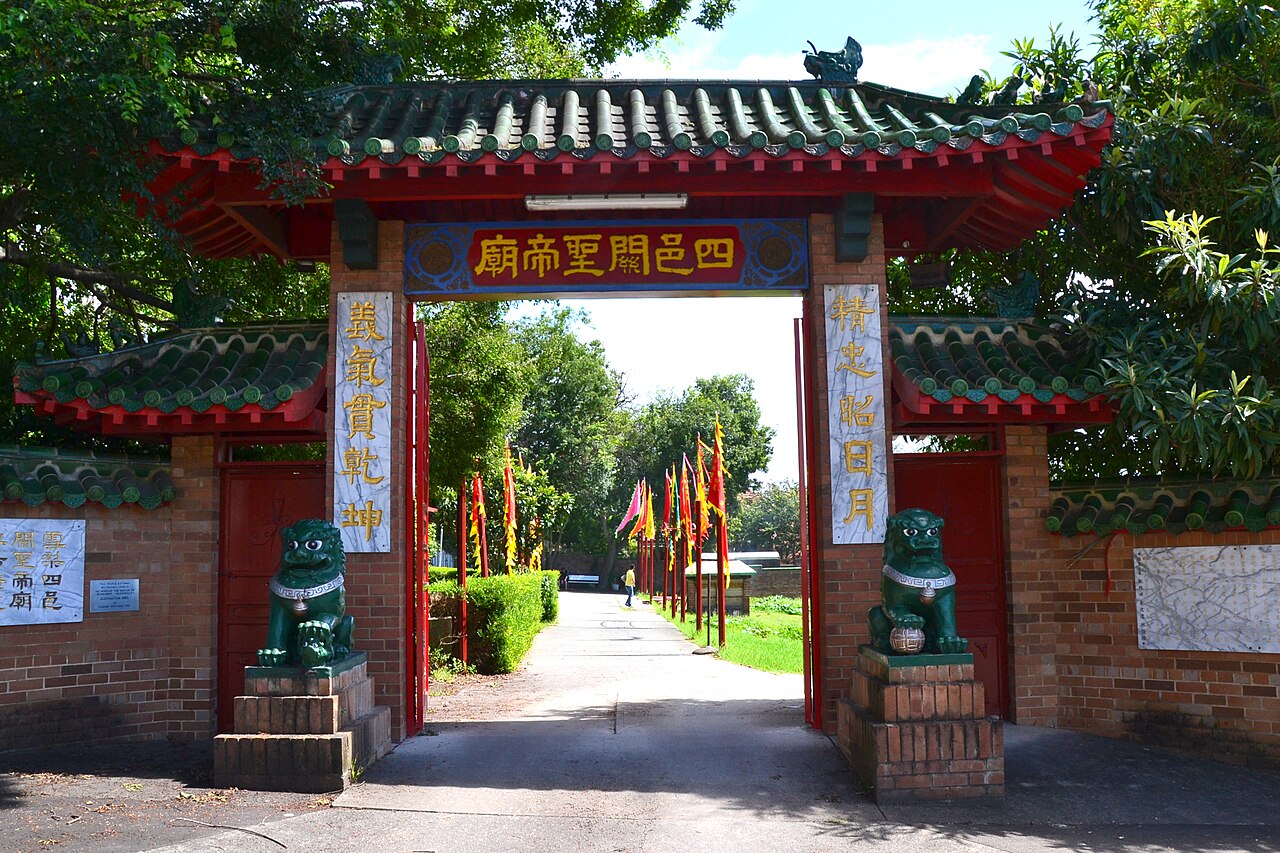 The entrance gateway of Sze Yup Temple, with green roof tiles, red beams, Chinese inscriptions and guardian lions, photographed in 2012.