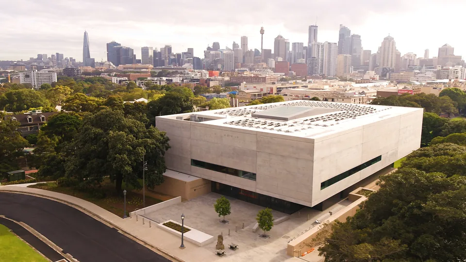 Aerial view of Chau Chak Wing Museum at the University of Sydney, with the city skyline beyond.