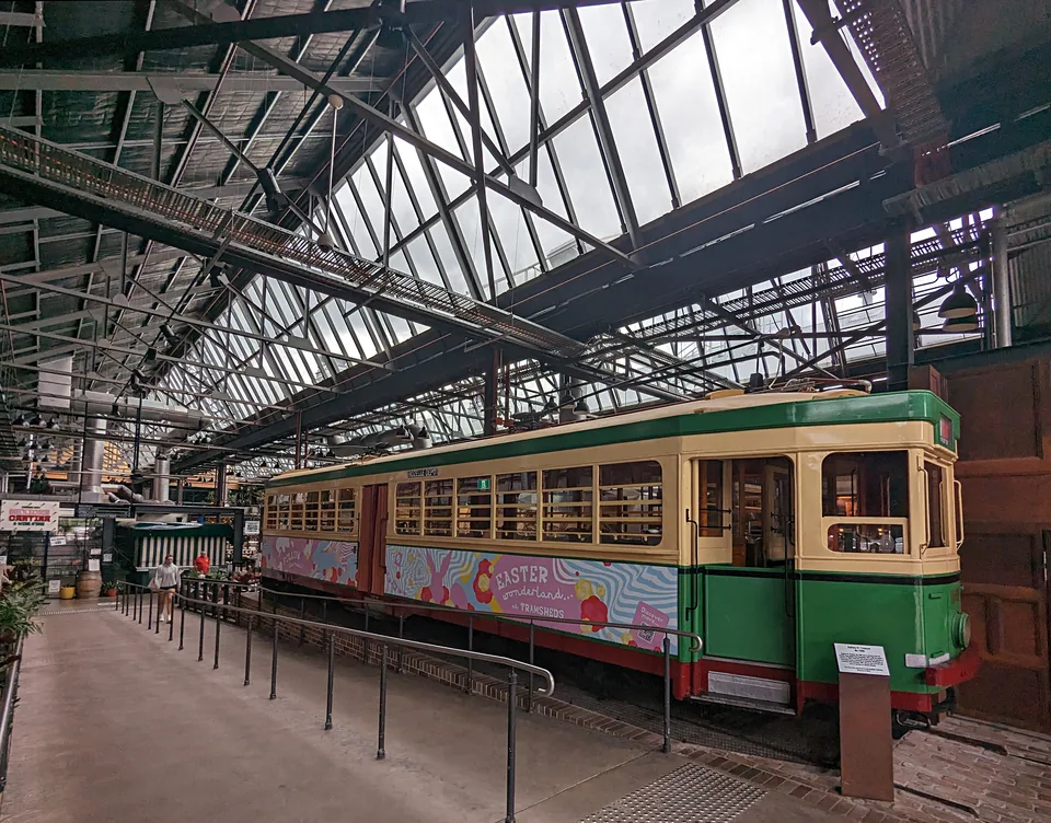 Restored tram number 1995 beneath the industrial roof inside Tramsheds.