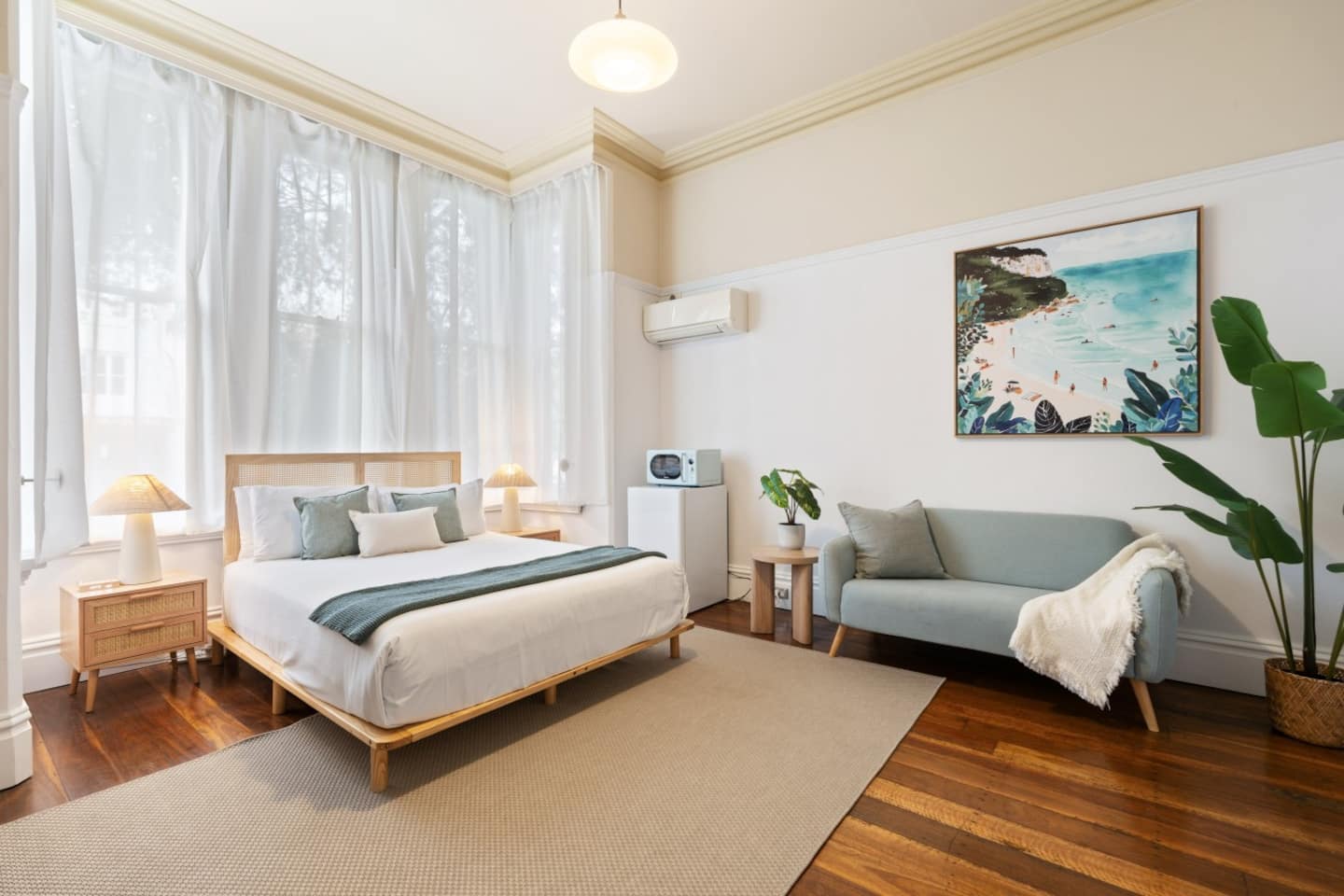 The Coastal Salon with the bed, sitting area and coastal artwork